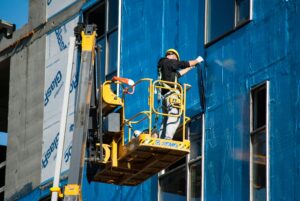 Worker Insulating a Building from the Skylift Basket